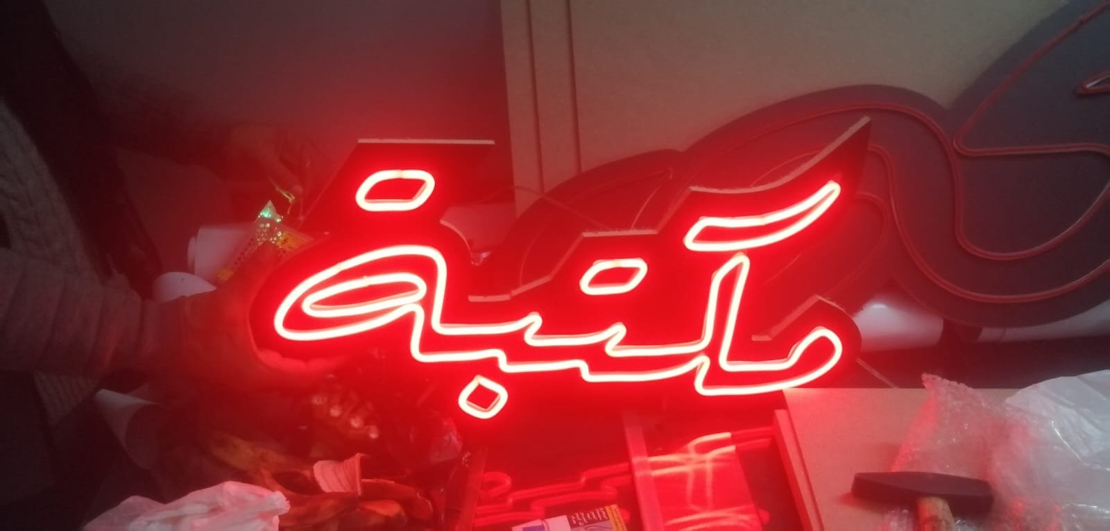 لافتة نيون حمراء بكلمة مكتبة بخط عربي مموج