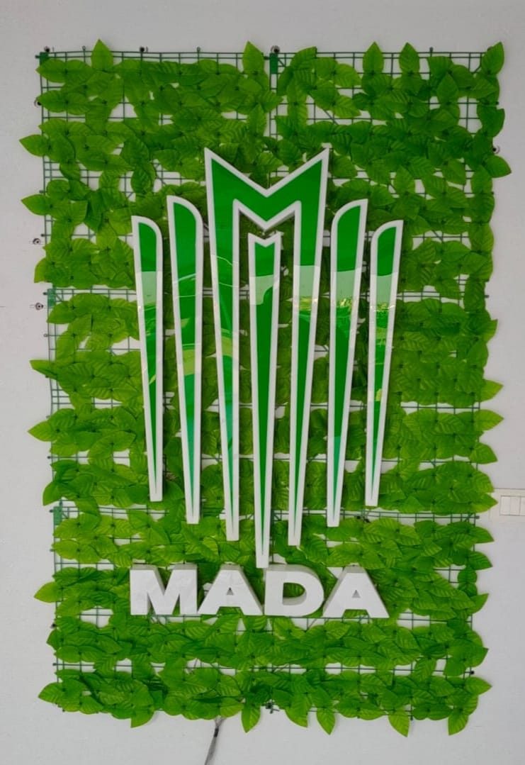 لافتة MADA على جدارية عشب صناعي أخضر